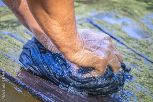 The daily life of the riverside in this detail of a person doing laundry on the banks of a river.