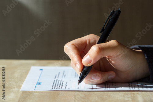 Closeup of woman's hand holding a pen filling out a census form.