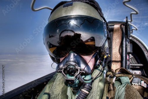 Royal Air Force ( RAF UK ) Pilot in the cockpit in an ejector seat wearing helmet, visor and oxygen mask flying high above the clouds Top Gun style fighter pilot black visor