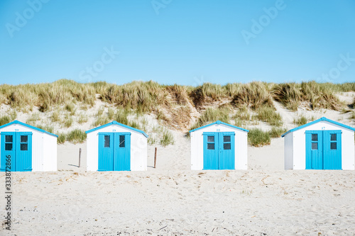 Texel Island Netherlands, blue white beach hut on the beach with on the background the sand dunes of Texel Holland, cabin on the beach