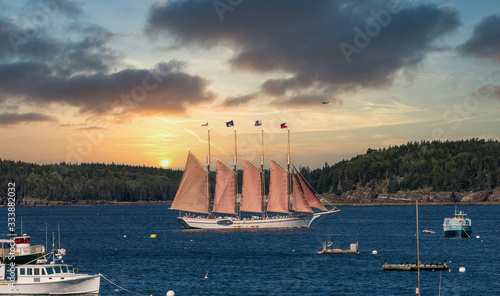 A four masted schooner touring sightseers through a blue harbor off Bar Harbor, Maine