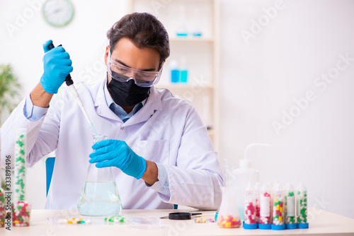 Young male chemist in drug synthesis concept