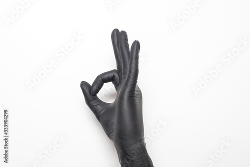 Medical glove in black on a white background. Hand showing okay sign.