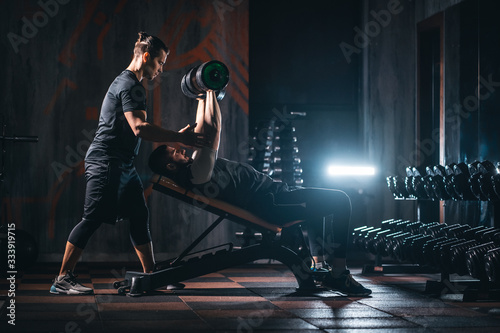 young man has workout with personal trainer in modern gym