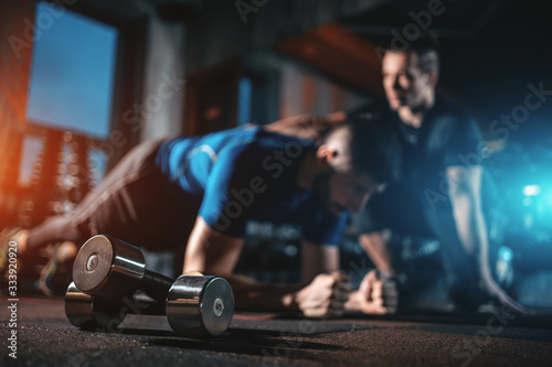 young man has workout with personal trainer in modern gym