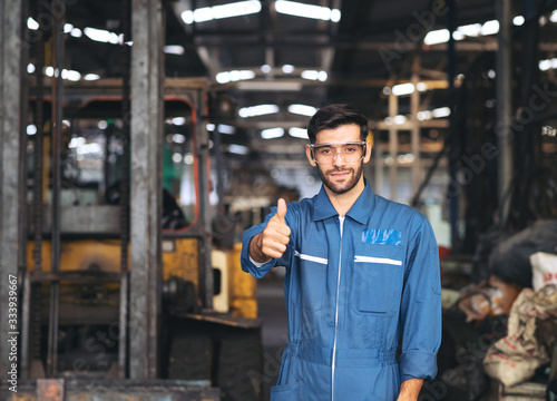 Portrait of an industrial man engineer standing and show his thumb in the factory