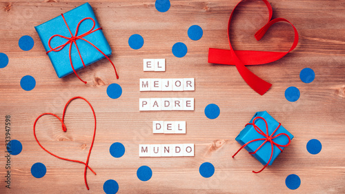 El mejor papa del mundo words that mean best dad in the world made of wooden blocks with blue gift boxes and red hearts on wooden background. Happy fathers day greeting card, top view