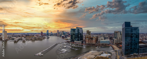 Aerial view of colorful, yellow, orange, red, blue sunset sky of the Inner Harbor of Baltimore Maryland with sky scrapers and sailboats 