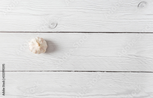 Head of garlic on white wood background