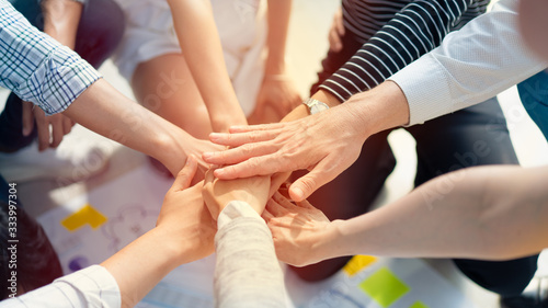 Background of diversity human bare hands join together in the middle under with warm natural sun light, Concept power of social network or volunteer's to be unity help and support the network society.