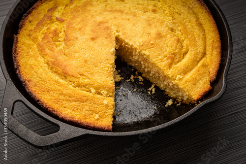 Fresh cornbread right out of the oven baked in a cast iron skillet with a slice removed