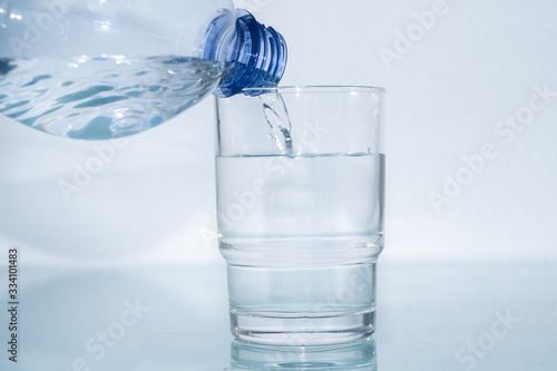 Mineralwasser aus Plastikflasche in das Glas giessen