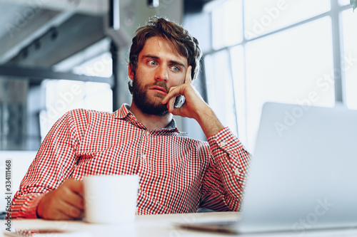 Puzzled thoughtful businessman sitting at his working table in an office. Business concept