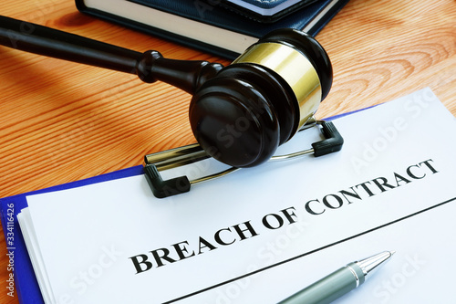 Breach of contract papers with pen and gavel.