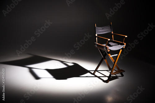 Directors chair stands in the beam of light. Space for text. Vacant chair. The concept of selection and casting. Shadow and light.