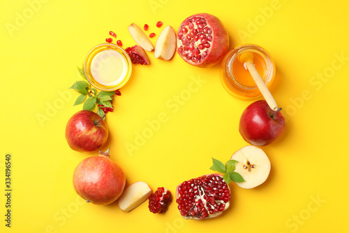 Apple, honey and pomegranate on yellow background, space for text