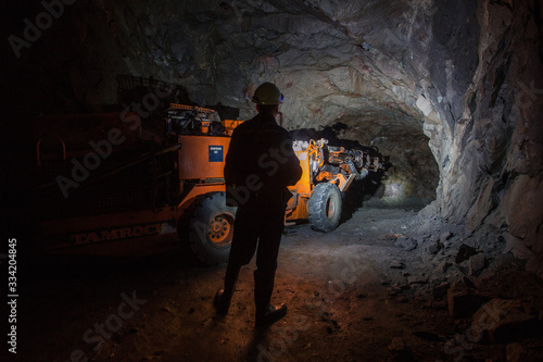 Man miner in underground quartz mine tunnel with scoop machine