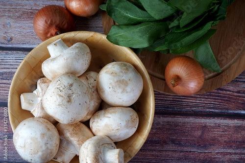 Mushrooms, spinach and onions on a wooden table