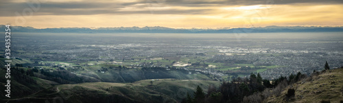 Panoramic sunset shot of city with mountains backdrop. Shot at Port Hills above Christchurch, New Zealand