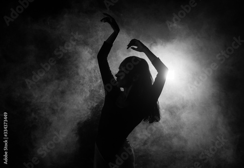 Female silhouette dancing in shadow and smoke