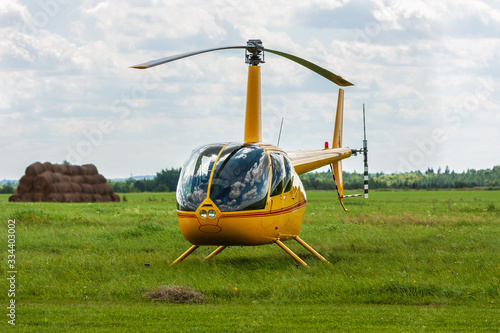 A yellow helicopter parked at an airfield