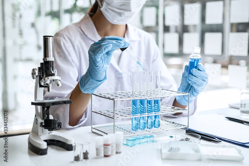 Biochemistry laboratory research, Scientist or medical in lab coat holding test tube with Using Microscope reagent with drop of color liquid over glass equipment working at the laboratory