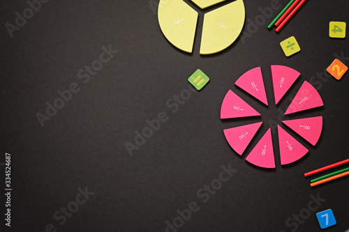 Mathematics background - fractions on black table, close up. Dividing fractions, math concept.