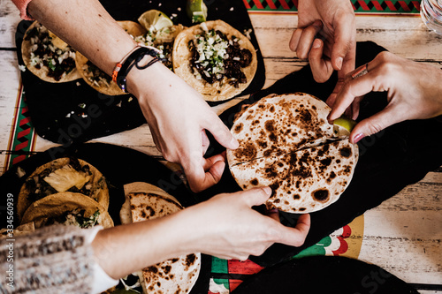 unrecognizable group of friends eating mexican food in a restaurant. Delicious fajitas. Lifestyle outdoors