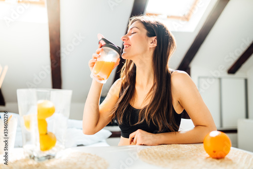 Woman at home drinking orange flavored amino acid vitamin powder.Keto supplement.After exercise liquid meal.Weight loss fitness nutrition diet.Immune system support.Organic citrus fruit.Strong body