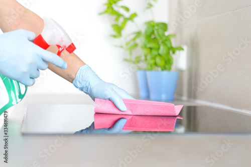 Woman in gloves cleaning kitchen. 