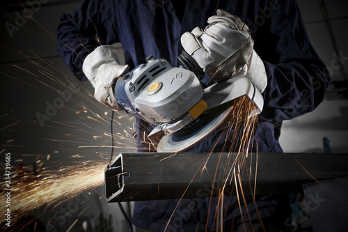 Close up on a man hold an angle grinder to cut an iron with sparks