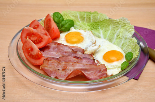  breakfast bacon and fried eggs with vegetables on a plate