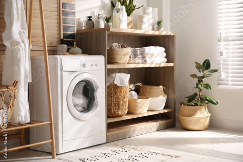 Modern washing machine and shelving unit in laundry room interior