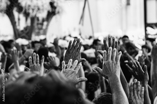 Mãos erguidas de pessoas. Multidão em procissão religiosa. Muitas mãos levantadas.