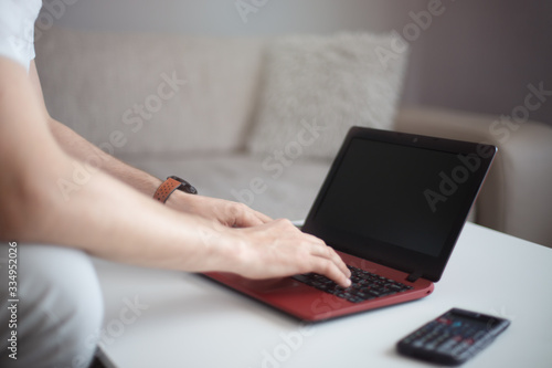 Młody mężczyzna piszący na klawiaturze z laptopa. 