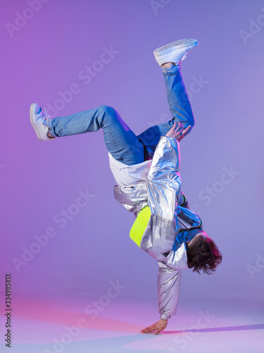 Cool guy dancing contemporary dance in studio. Neon light background. Acrobatic bboy dancer. Break dance lessons.