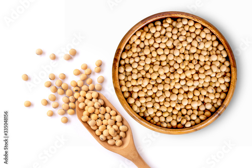 Closeup soy beans in wooden bowl and scoop isolated on white background. Overhead view. Flat lay.