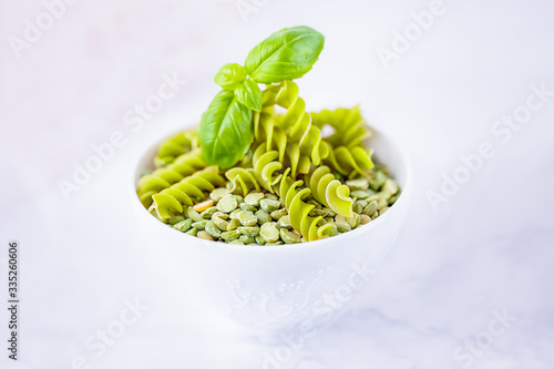 Gluten free green pea fusilli pasta and dry split light green peas on a white background, copy space