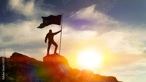 Man with flag on top of the mountain against the sky. Concept business ideas, success and achievement, winner leader.