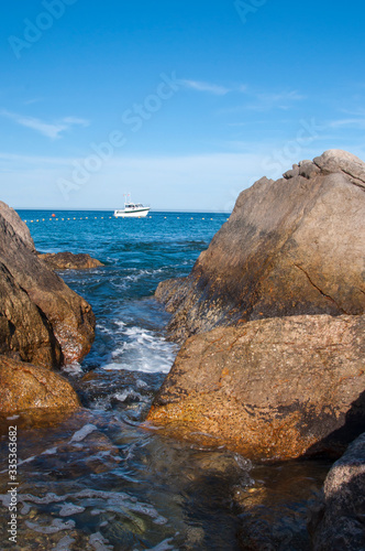 Set of rocks on the shore of the blue sea with boat in the distance