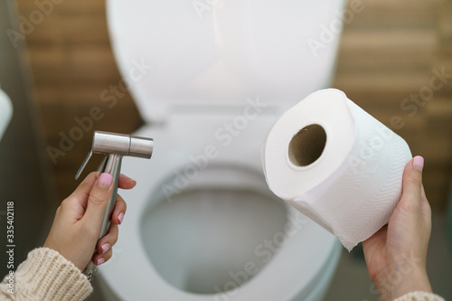 Woman make a choice, bidet shower or toilet paper.