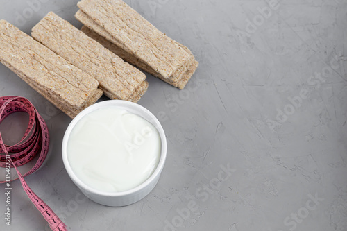Diet crispbread with bran on a light background. Near a centimeter and homemade yogurt. The concept of losing weight. Healthy eating vegetarian cookies.