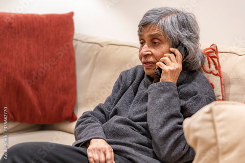 Old elderly woman talking on a phone while self isolating