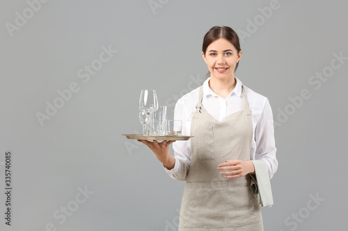 Portrait of female waiter on grey background