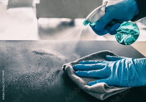 Surface sanitizing against COVID-19 outbreak. Home cleaning spraying antibacterial spray bottle disinfecting against coronavirus wearing nitrile gloves. Sanitize hospital surfaces prevention.