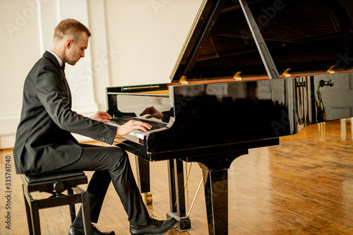 young handsome caucasian man in formal elegant suit gracefully play piano. professional pianist perform classic music