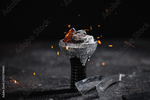 Closeup of a ceramic hookah or waterpipe head with alufoil or thin foil, sparkling hot coal