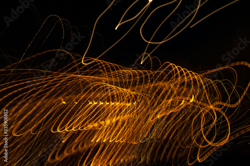 Gold light painting photography, long exposure photo of golden fairy lights in a loop against a black background.