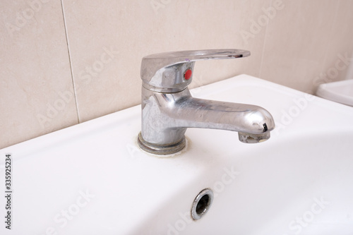 Dirty faucet with limescale, calcified water tap with lime scale on washbowl in bathroom, home cleaning concept