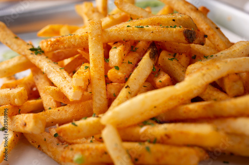 A closeup view of a tray of cajun style french fries in a restaurant or kitchen setting.
